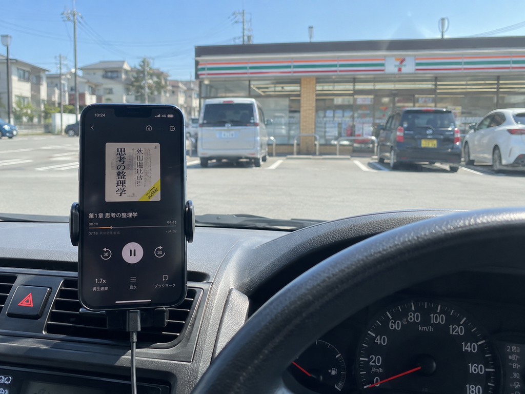 車内でAudibleを再生しているスマートフォンと停車中の営業車